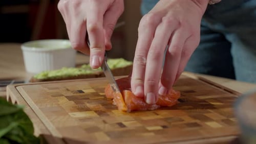Hands Slicing Fresh Salmon on Wooden Cutting Board
