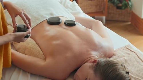 Female Client Having Hot Stone Massage at Spa