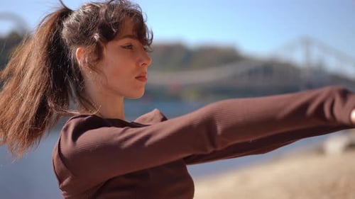 Young Woman Stretching Near River on Sunny Day