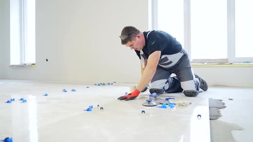 industrial tiler Professional builder worker installing floor a large ceramic tile at repair renovat