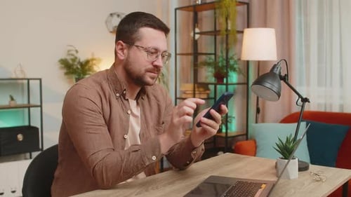 Man Using Smartphone While Working at Home Office