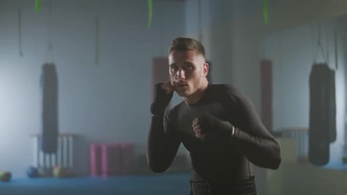 Fighter Trains His Punches and Defense in the Boxing Gym a Man Boxer Trains and Looks at the Camera