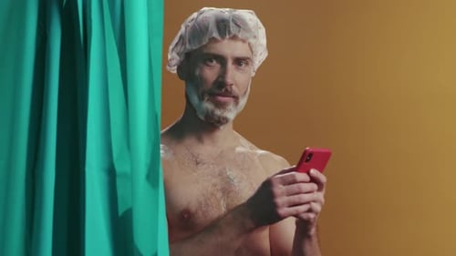 Casual Man Peeking Through Teal Curtain with Phone Funloving Man in Shower Using Phone Amid Bubbles