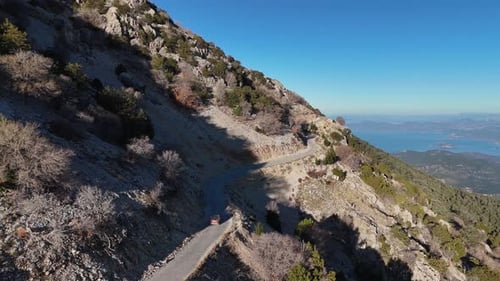 Aerial View of a Winding Mountain Road with Sea in the Background