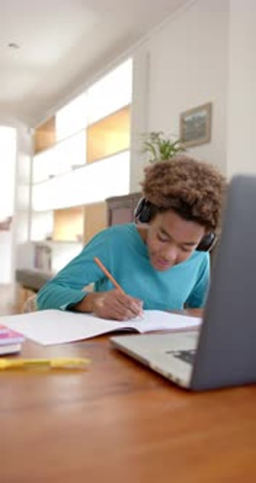 Teen Studying at Home With Laptop and Notebook