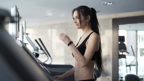 Brunette woman on treadmill building beauty and vitality in gym closeup