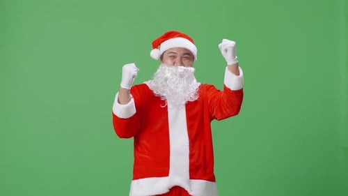 Happy Asian Man In Santa Suit Celebrating The Success While Standing On Green Screen In The Studio