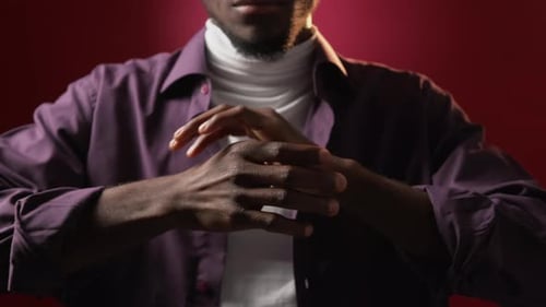 Man Rubs His Knuckles Against Red Backdrop