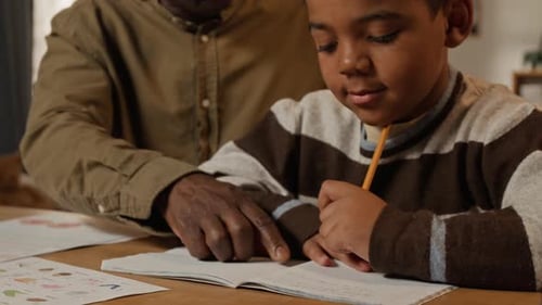 Caring Black Grandfather Assisting Young Grandson with Homework