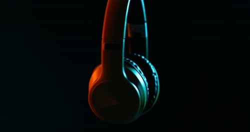 Wireless Headphones Rotating with Neon Lights on Black Background