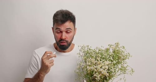 Man with Red Eyes Holding Flowers Uses Tissue