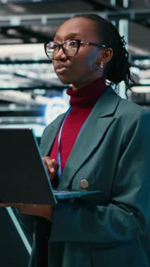Vertical Video Female Programmer Walking in Data Center Engineer Uses AR Simulation and Laptop