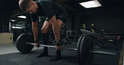 Dedicated Young Man Lifting Heavy Weights in Modern Gym