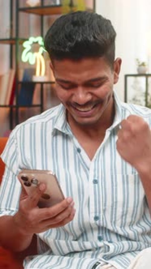 Excited Young Man Celebrates Success While Using Phone