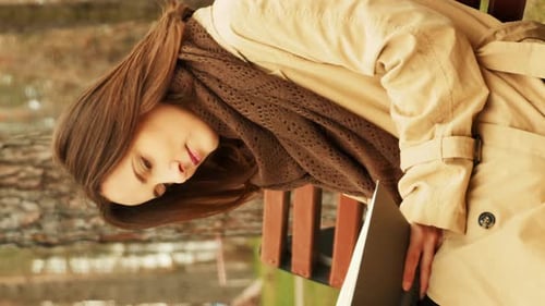 Woman reading book sitting on bench in autumn park