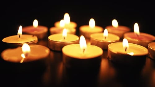 Glowing Tea Light Candles Flicker in the Darkness