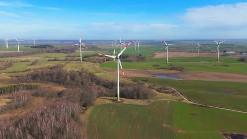 drone footage of wind turbines in a wind farm generating green electric energy on a wide green field