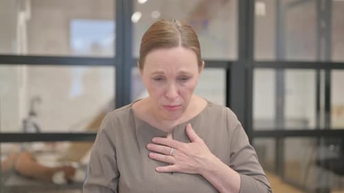 Portrait of Coughing Sick Senior Businesswoman in Office