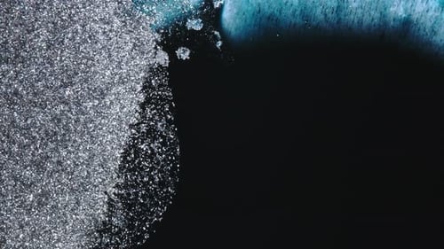Abstract silver glitter blending into blue liquid with cinematic motion and elegance