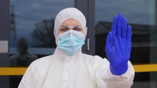Woman in protective suit holding hand up