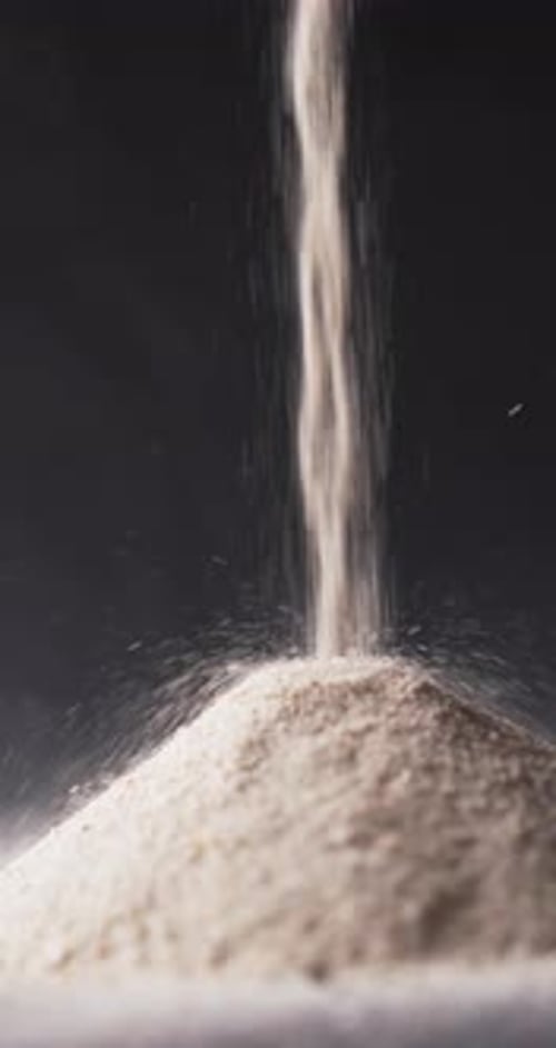 Vertical video of close up of heap of sand grains and copy space on black background