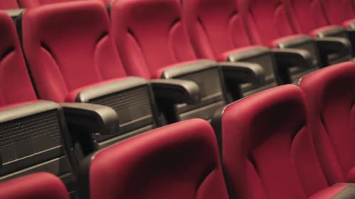 Slow revealing shot of folded red empty cinema seats with numbers