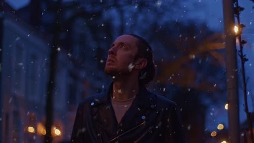 Man Walks in Snow at Night in City