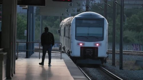 Train Arrives at Station As Traveler Waits at Platform in