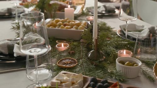 Table de fêtes avec plats, branches de pin, bougies, tranches d'orange séchées