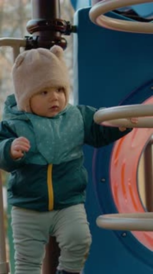 Vertical video Baby joyfully explores playground slides and takes first steps