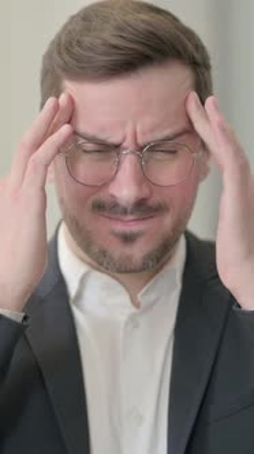 Man in Suit Rubbing Temples in Discomfort
