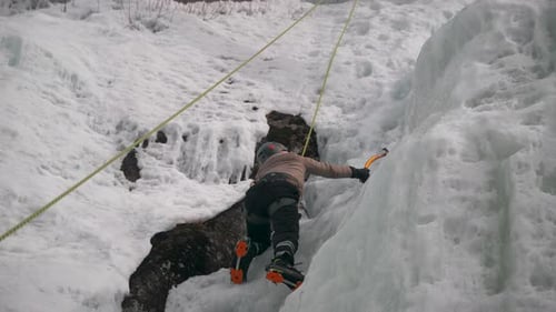 A person uses crampons and ice axe to climb a frozen glacier