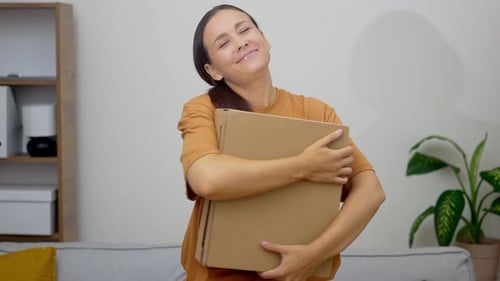 Happy Housewife Rejoices at Received Package with Orders Standing in Living Room with Big Sofa