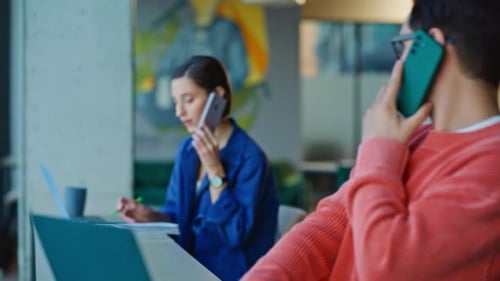 Coworkers Talking on Phones in Open Office