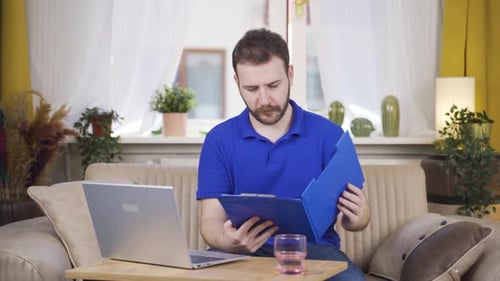 Man Works with Laptop and Folder at Home