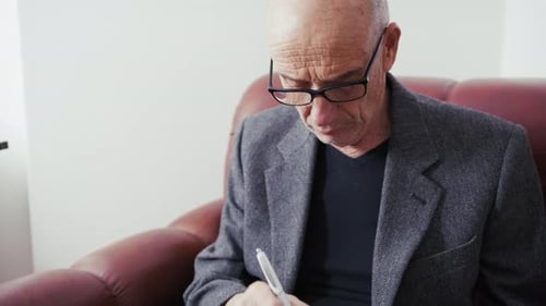 Mature Adult Writing with Pen Indoors