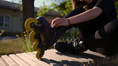 young beautiful girl in park tying laces on roller skates before skating workout active lifestyle