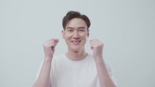 Young smiling man holding Invisalign braces over white background studio