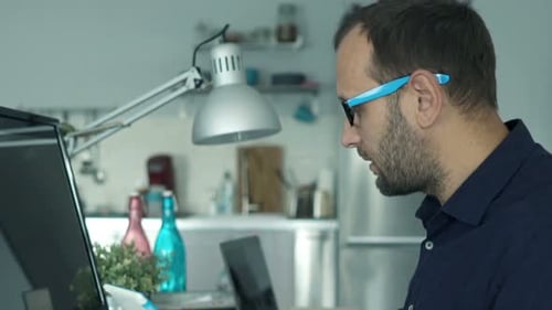 Junger kaukasischer Mann arbeitet zu Hause in einer modernen Wohnung an Tablet und Computer