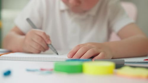 Child Drawing in Notebook with Pen, Close-Up