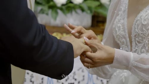 The bride is putting a wedding ring on the groom during the wedding ceremony in the church
