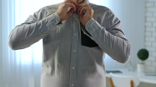 Man buttons up and rolls up sleeves