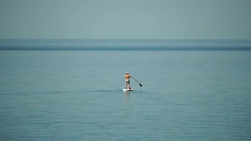 Sea Man Sup Athlete Man Floating in Calm Sea and Paddleboarding at Summer Sunset Healthy Strong Male