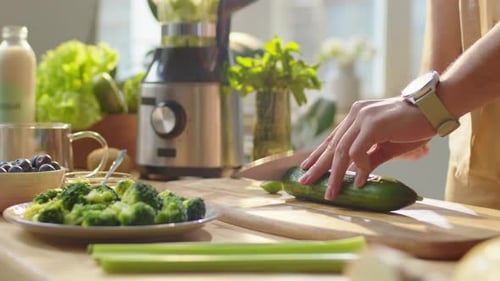 Man Cutting Fresh Cucumber at Kitchen Table