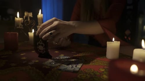 Nahaufnahme einer Frau, die auf dem Tisch sitzt und ein paar Tarotkarten aus dem Deck pflückt für