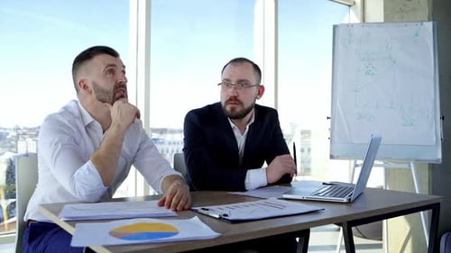 Businessmen Discussing Data at Office Conference Table