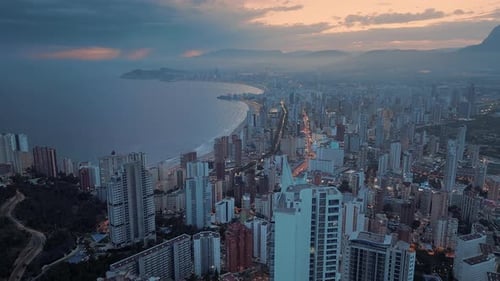 Busy modern coastal city at dusk. Beautiful orange sunset above the seafront town.