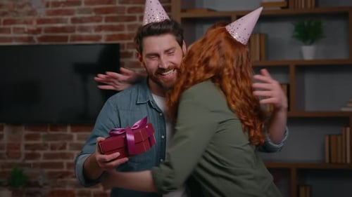 Two Caucasian Friends Couple at Home Party Birthday Congratulation Woman Congratulate Man Giving