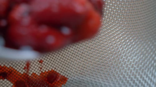 Raspberries Being Poured Through a Metal Sieve