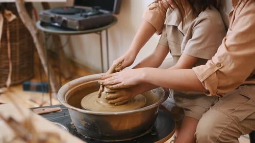 Mother Helping Girl Shape Clay on Pottery Wheel